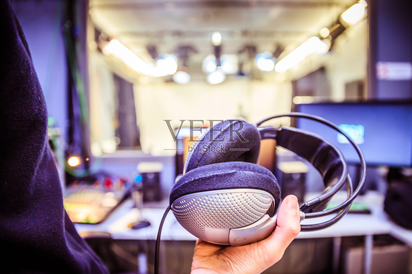 錄音室錄音:一個戴著耳機(jī)的年輕人正坐在錄音室里,錄音室的背景模糊不清